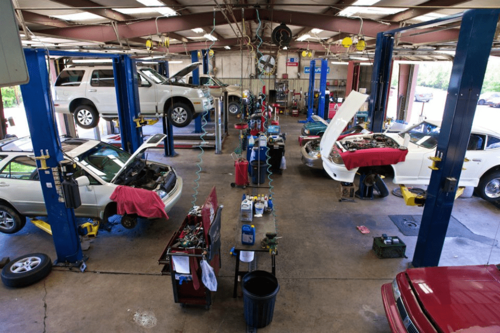 auto repair costs, auto repair in north little rock at Cantrell Service Center. Busy automotive repair shop with multiple vehicles on hydraulic lifts, open hoods, and diagnostic equipment in use across several service bays.