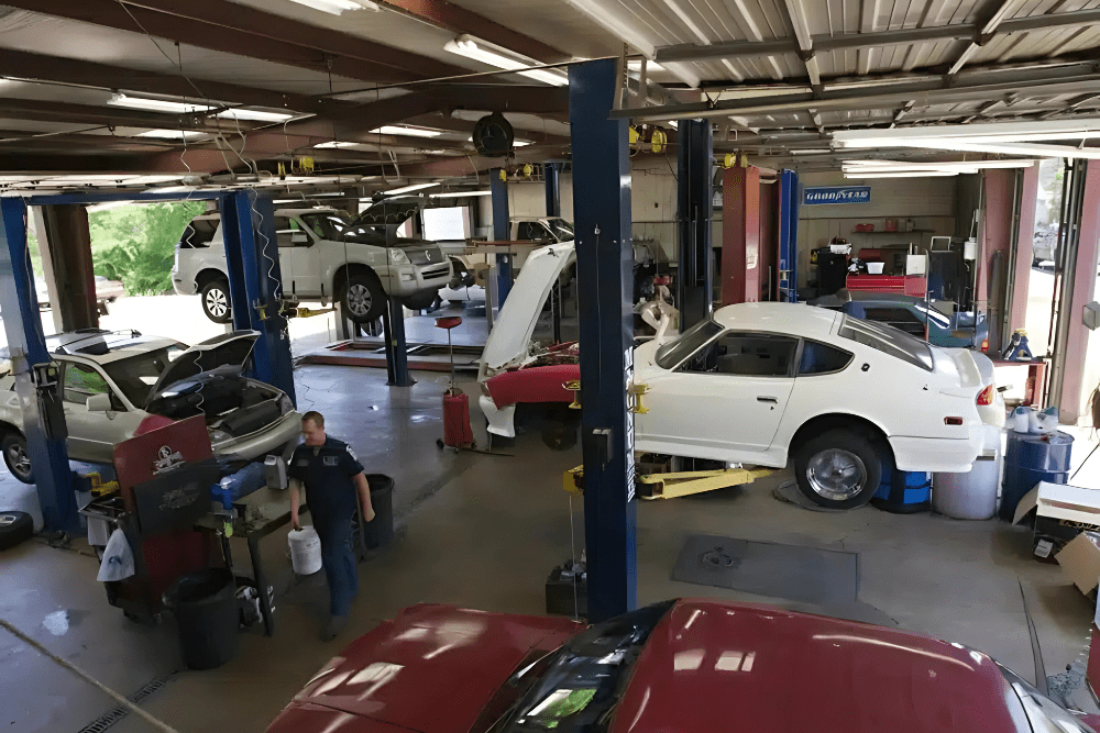 Back-to-school car maintenance in North Little Rock, AR by Cantrell Service Center. Image of multiple vehicles, including a classic white Datsun, lifted in a busy shop, showcasing the team’s expertise in maintaining both modern and vintage cars with safety and precision.