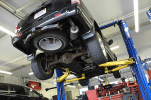 Drivetrain repair, auto repair in North Little Rock, AR by Cantrell Service Center. Image of an SUV lifted on a hydraulic hoist with the undercarriage exposed, highlighting suspension components, exhaust system, and drivetrain inspection during routine vehicle maintenance and repair.