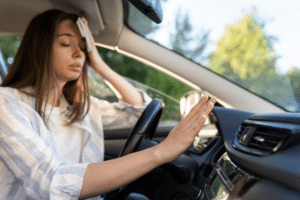 Car a/c blowing warm air, auto repair in North Little Rock, AR at Cantrell Service Center. Image of a woman driver struggling with heat inside the vehicle, highlighting the importance of reliable car A/C performance and cooling system service.
